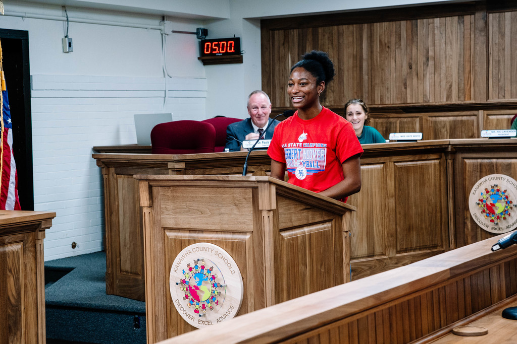 HHHS volleyball player speaking at the board meeting as board members look on from behind her. 