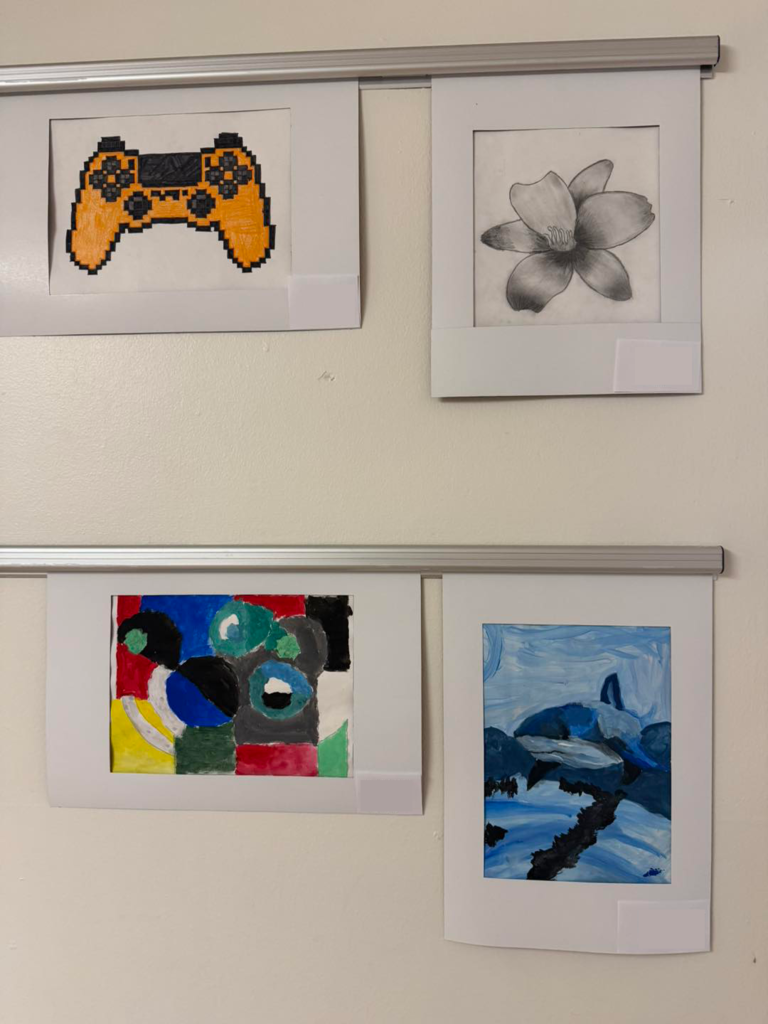 Four pieces of student art hanging on a wall at West Side Middle School.