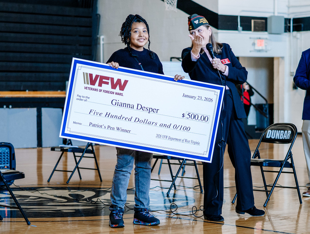 Gianna smiling at the camera, while holding her oversized check for 500 dollars that she got for winning the state title.