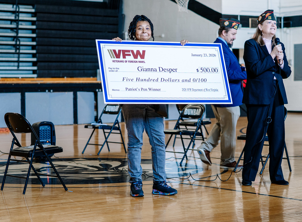 Gianna smiling at the camera, while holding her oversized check for 500 dollars that she got for winning the state title.