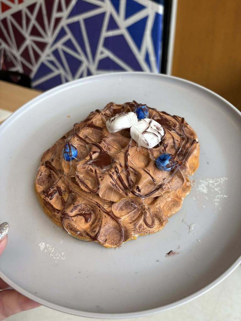 A sculpture made to look like a blueberry waffle covered in chocolate sauce in syrup. 