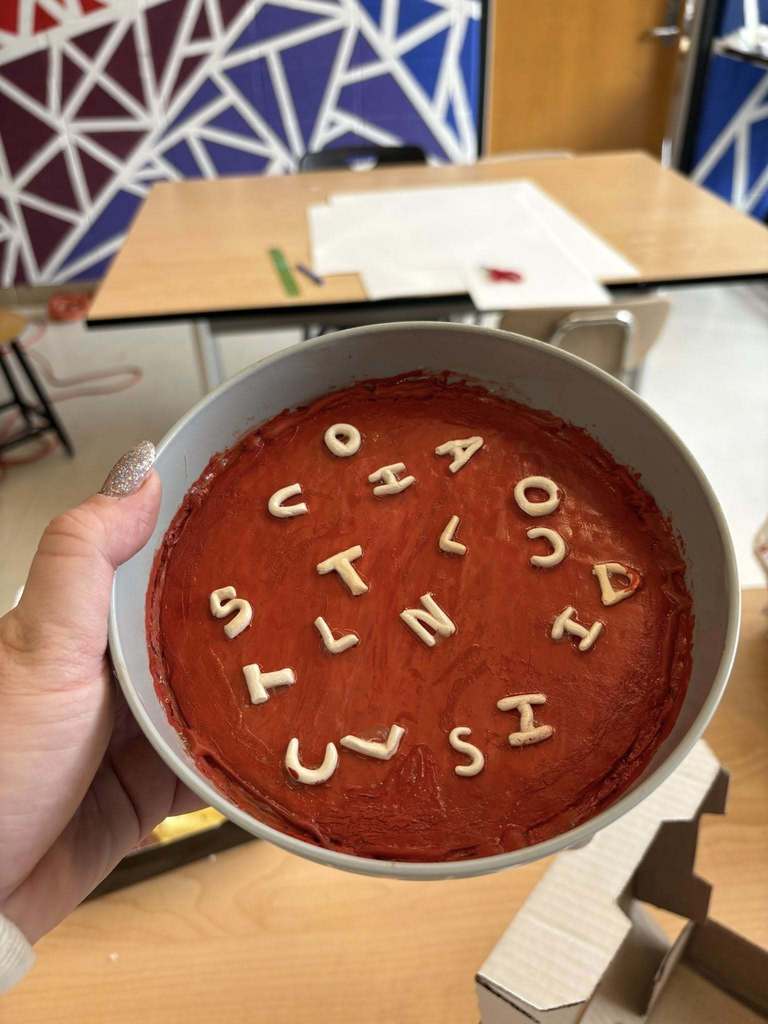 A sculpture made to look like tomato soup with noodles. The noodles are in the shapes of different letters of the alphabet. 