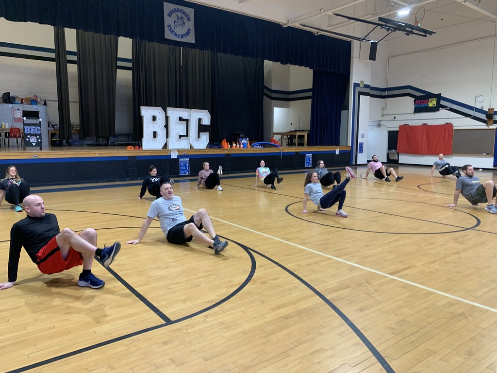 Teachers are spread out across the gym floor doing an exercise.