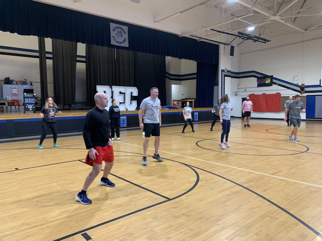 Teachers are spread out across the gym floor doing an exercise.