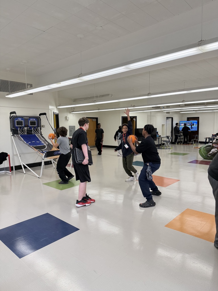 Students playing basketball on a mini basketball hoop in the game room. 