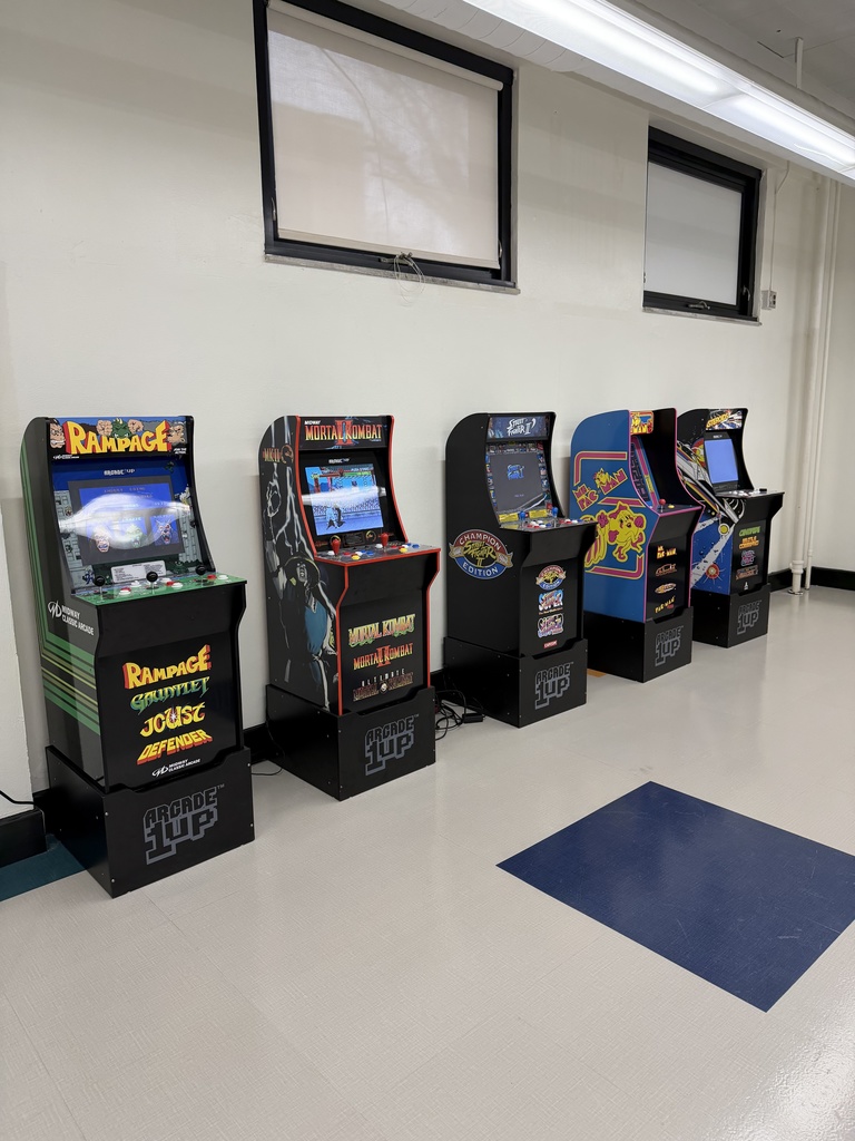 Five arcade games lining the wall in the game room at west side middle school. These are the old school, 90s era, type arcade games. 