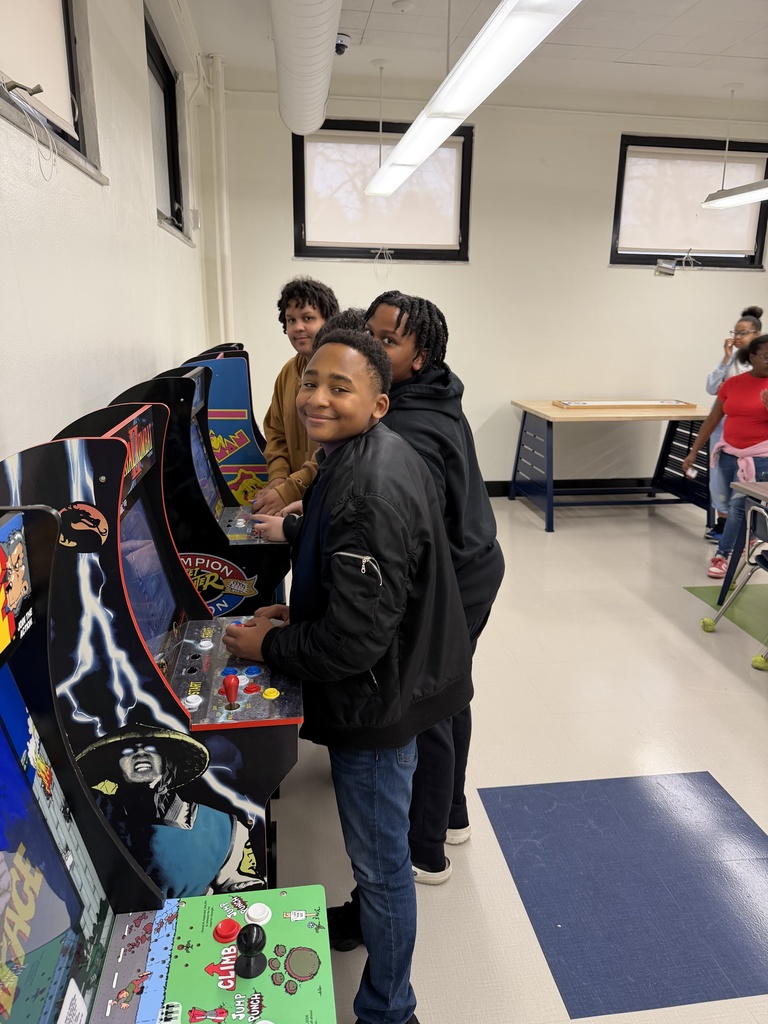 Four students taking a break from playing the arcade games to smile at the camera for a picture. 