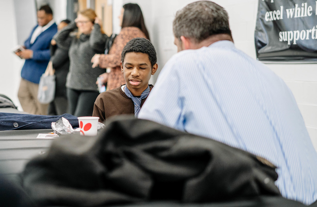 A mentor is speaking to an 8th grade student during the guys in ties event.