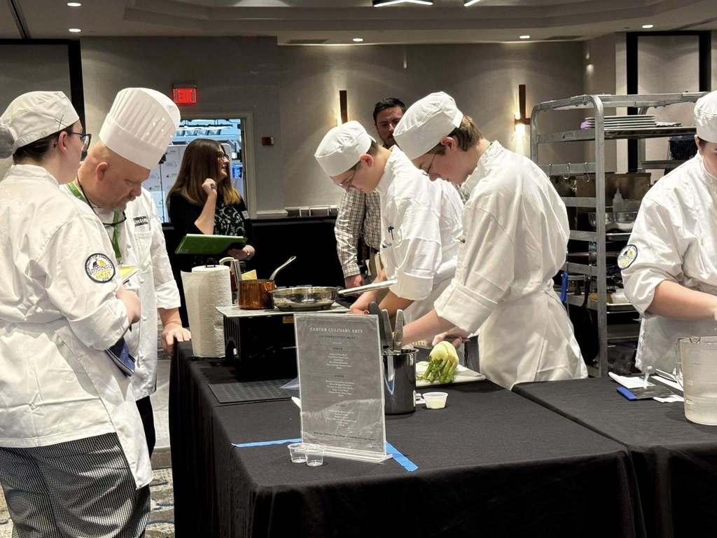 Culinary students are cooking food at their station. 