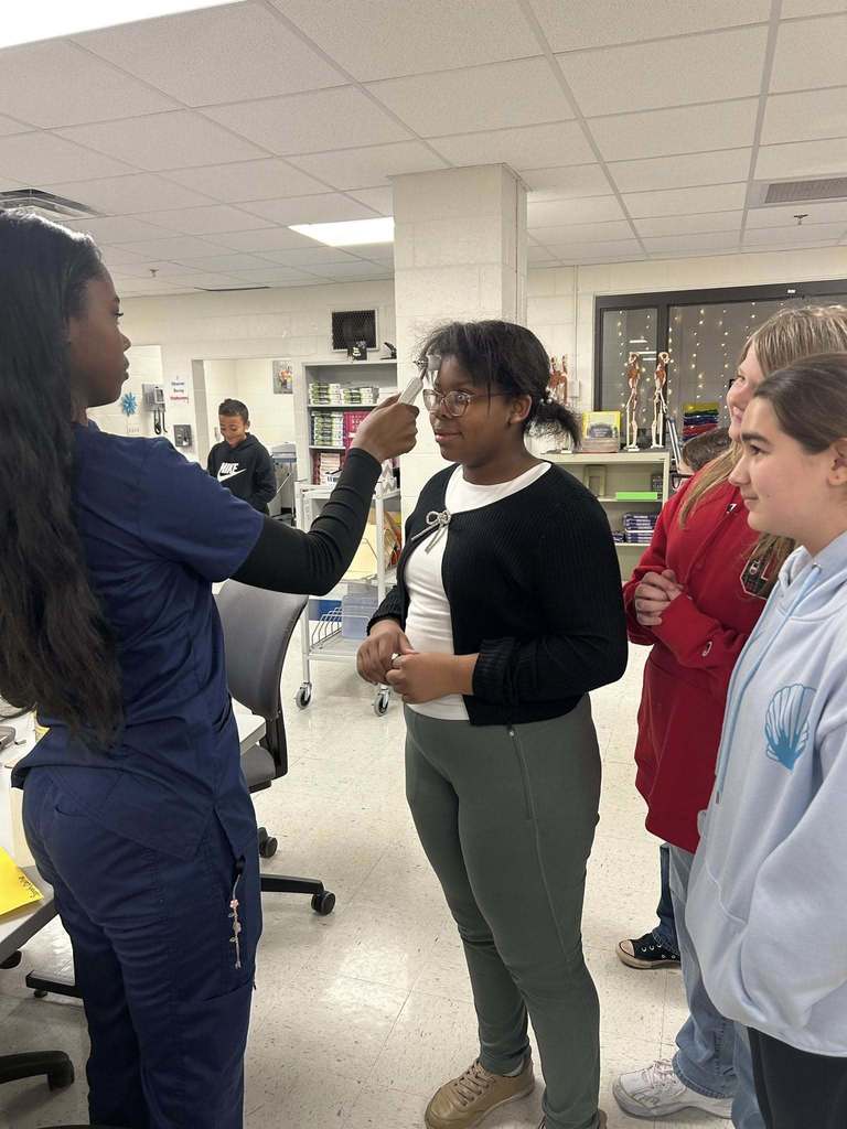 a ben franklin student using a forehead thermometer on a nitro elementary student.  