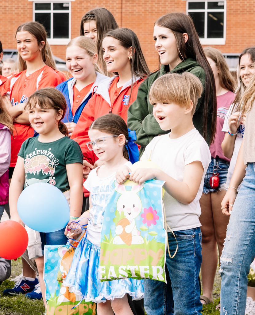 A crowd of students are smiling at the chemical reaction of the science experiment. The science experiment cannot be seen in the picture.