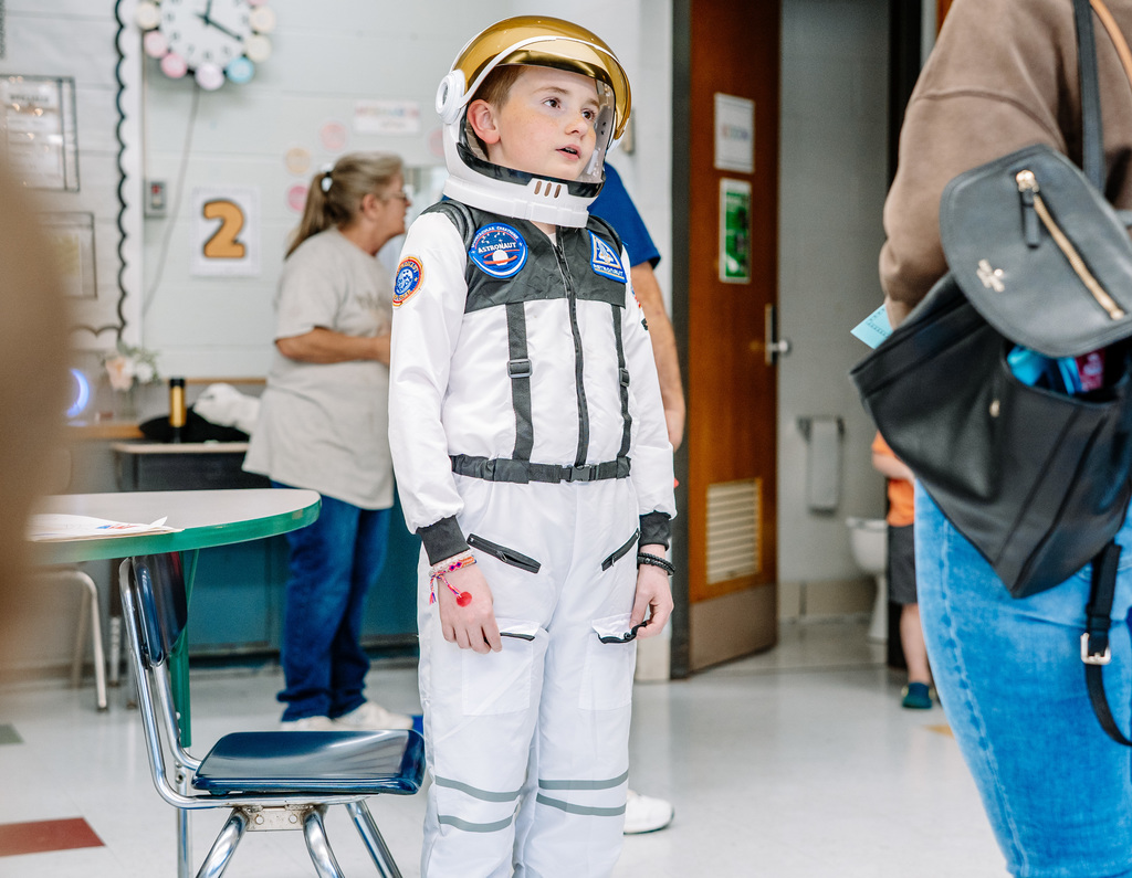 A student wearing a space suit and space helmet. 