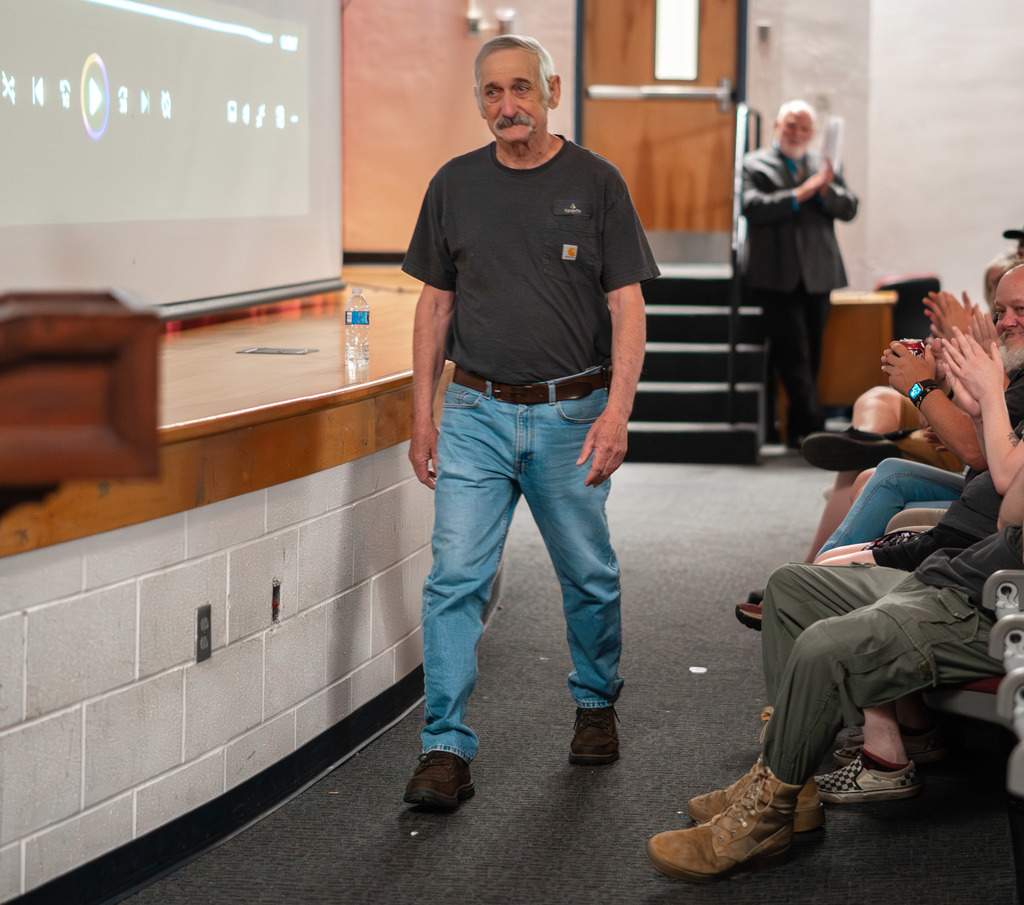 KCS Service Person of the Year, Kenneth Lacy, is walking to the front of the school auditorium. He is emotional. 