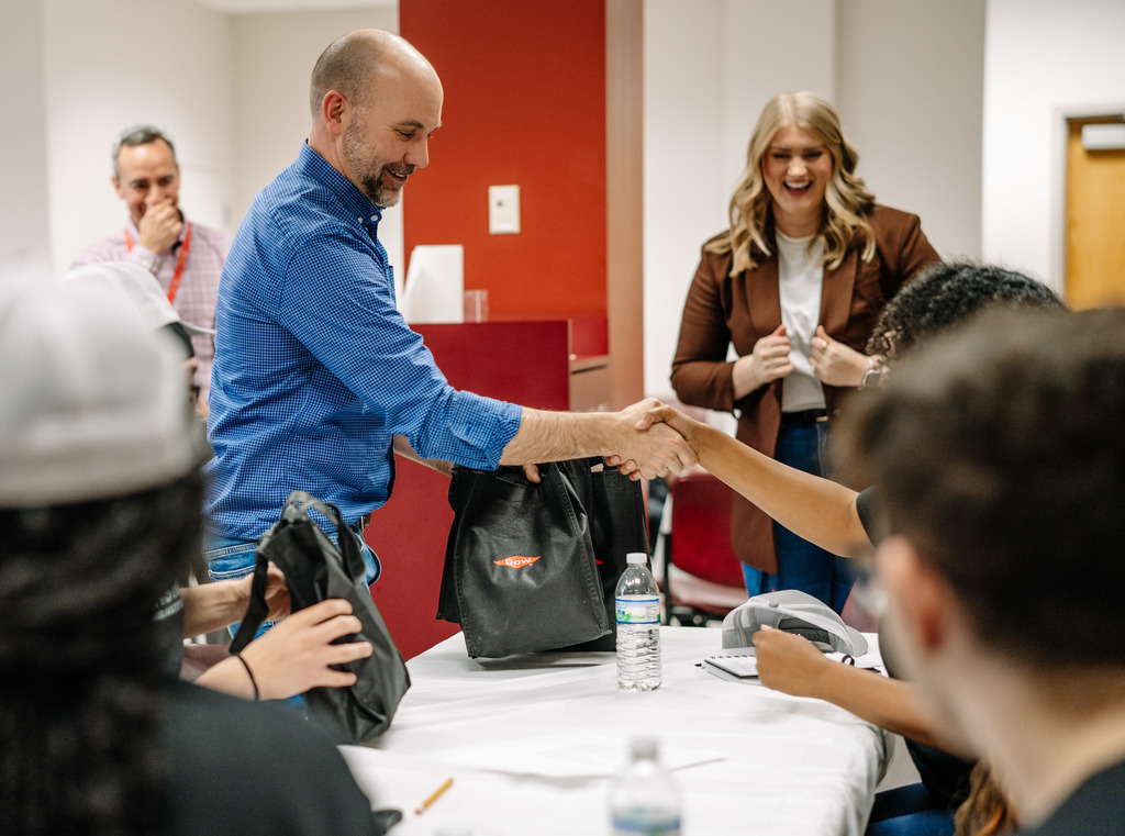 A Dow employee is shaking the hand of an SCHS student who won a prize during a DLI session. 