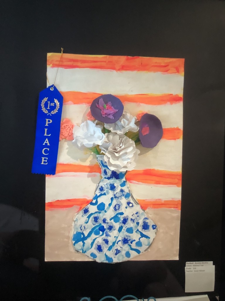 Artwork of a vase with colorful flowers against a striped background. A blue "1st Place" ribbon is attached, conveying achievement and pride.