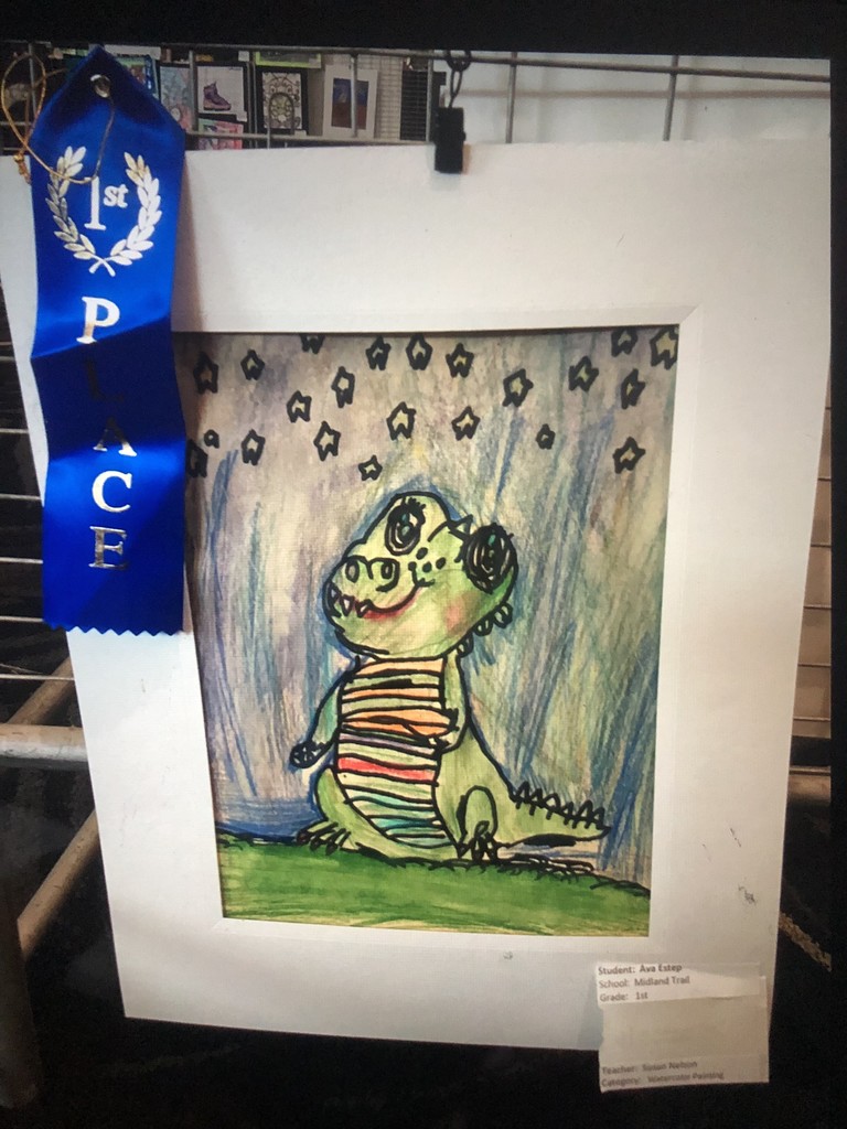 A colorful children's drawing of a whimsical dinosaur, wearing stripes, surrounded by stars. A blue "1st Place" ribbon is attached to the frame.