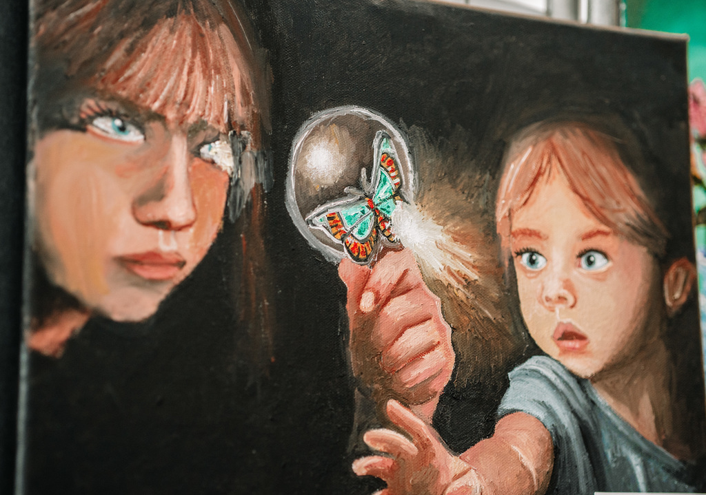 A painting of a woman looking at a butterfly through a magnifying lens and a young girl reaching for the butterfly.