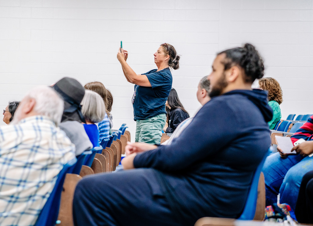 A parent taking a picture of her student signing the letter of intent. 