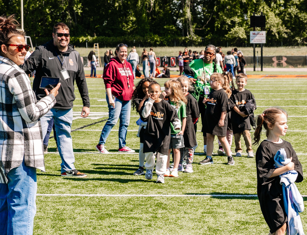 SCHS principal is wearing sunglasses and smiling, a young elementary student is laughing while covering her mouth.
