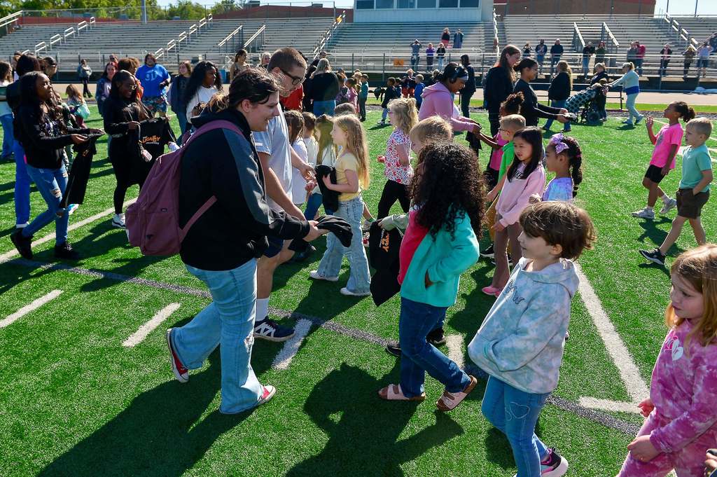 High school students and elementary students meeting at midfield on the football field. 