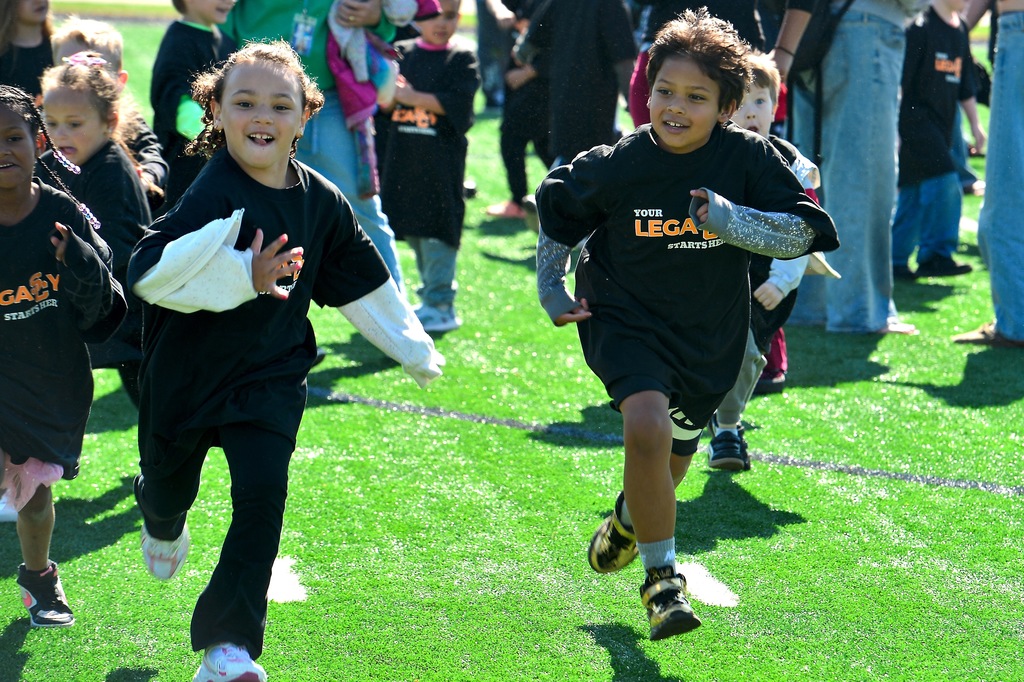 Young students running across a football field.