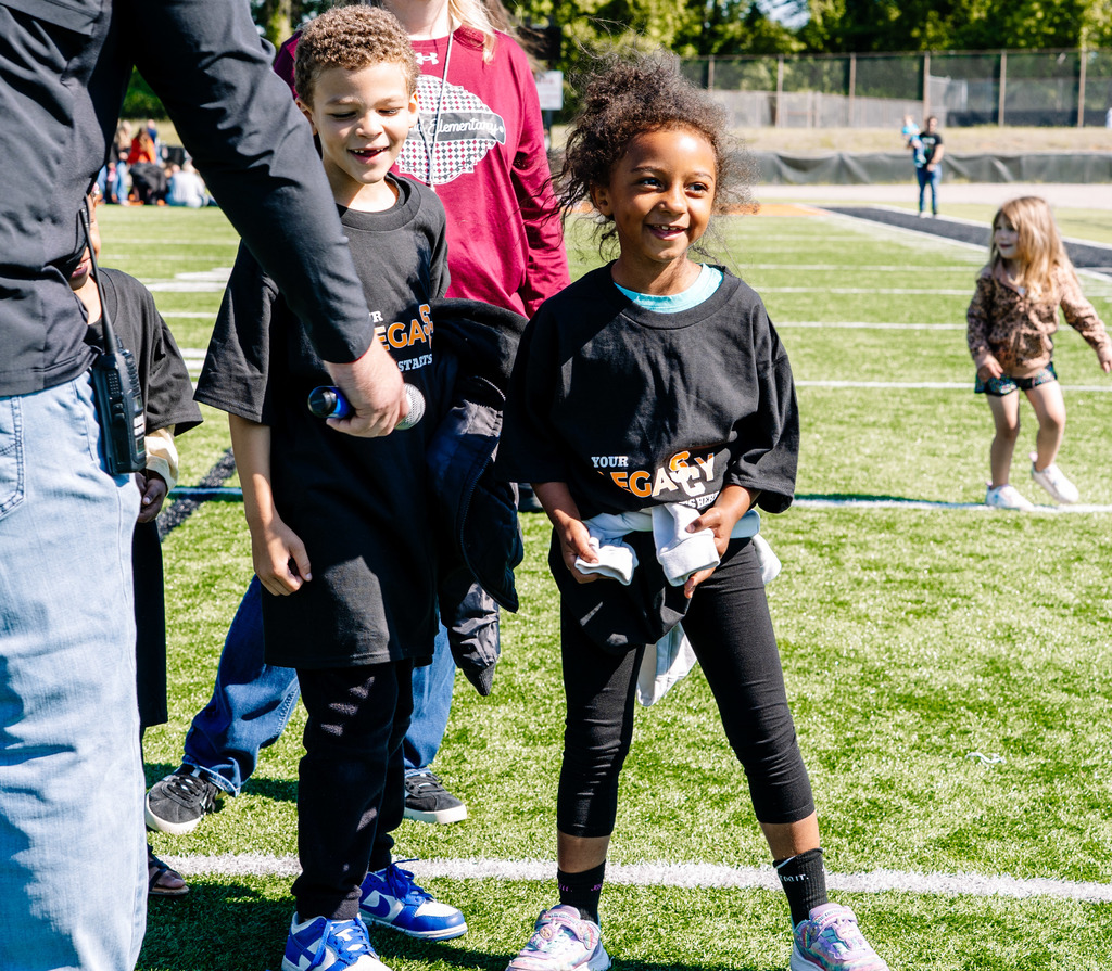 A young student is smiling on the football field.