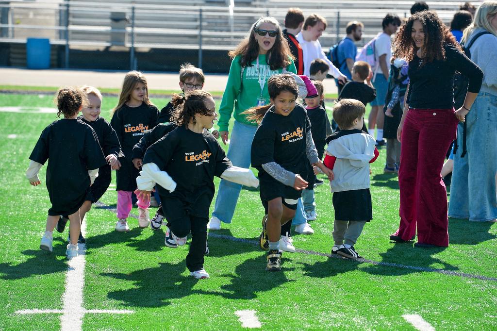 Young students running across a football field.