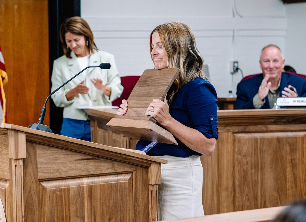 2026 KCS Educator of the Year, Cassie Allara, is holding her plaque and looking thankful as she steps up to the podium to say a few words after winning the award.