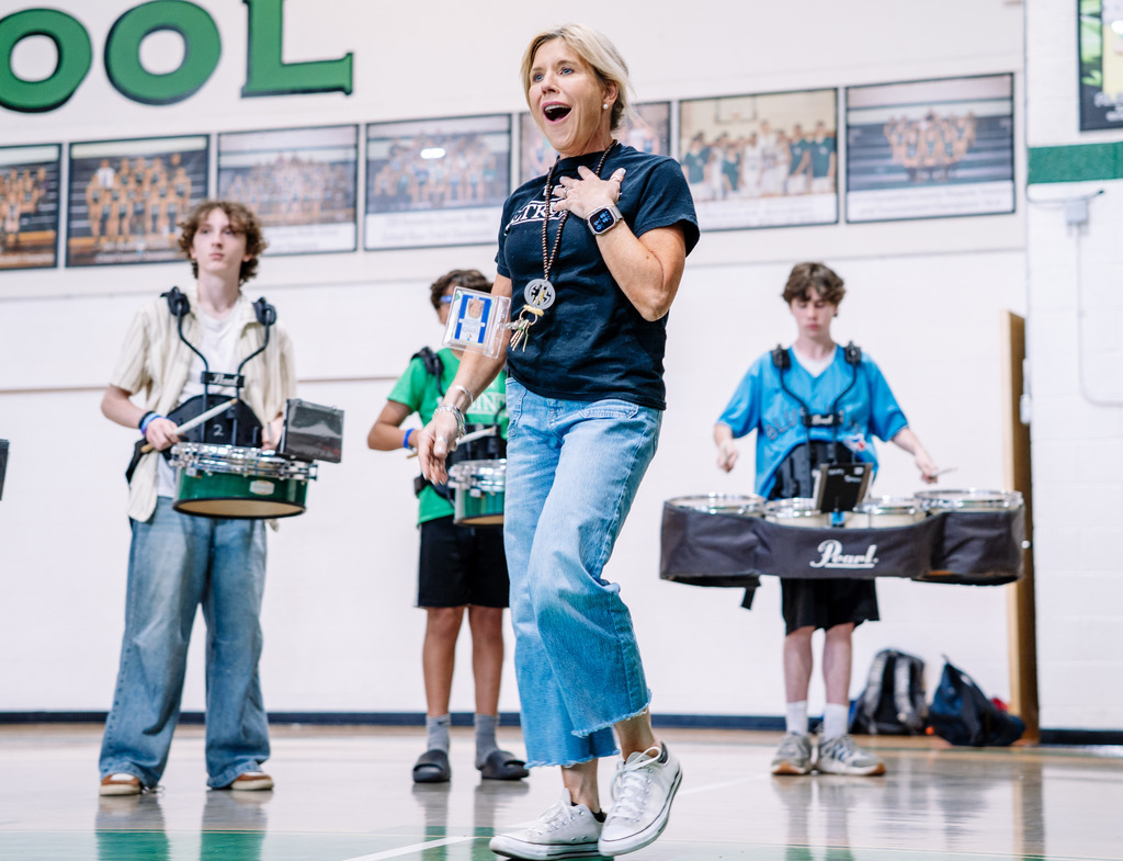 Horace Mann Prinicpal, Shandon Tweedy, in the school gym with a shocked impression on her face. Three students from the school band are behind her playing the drums.