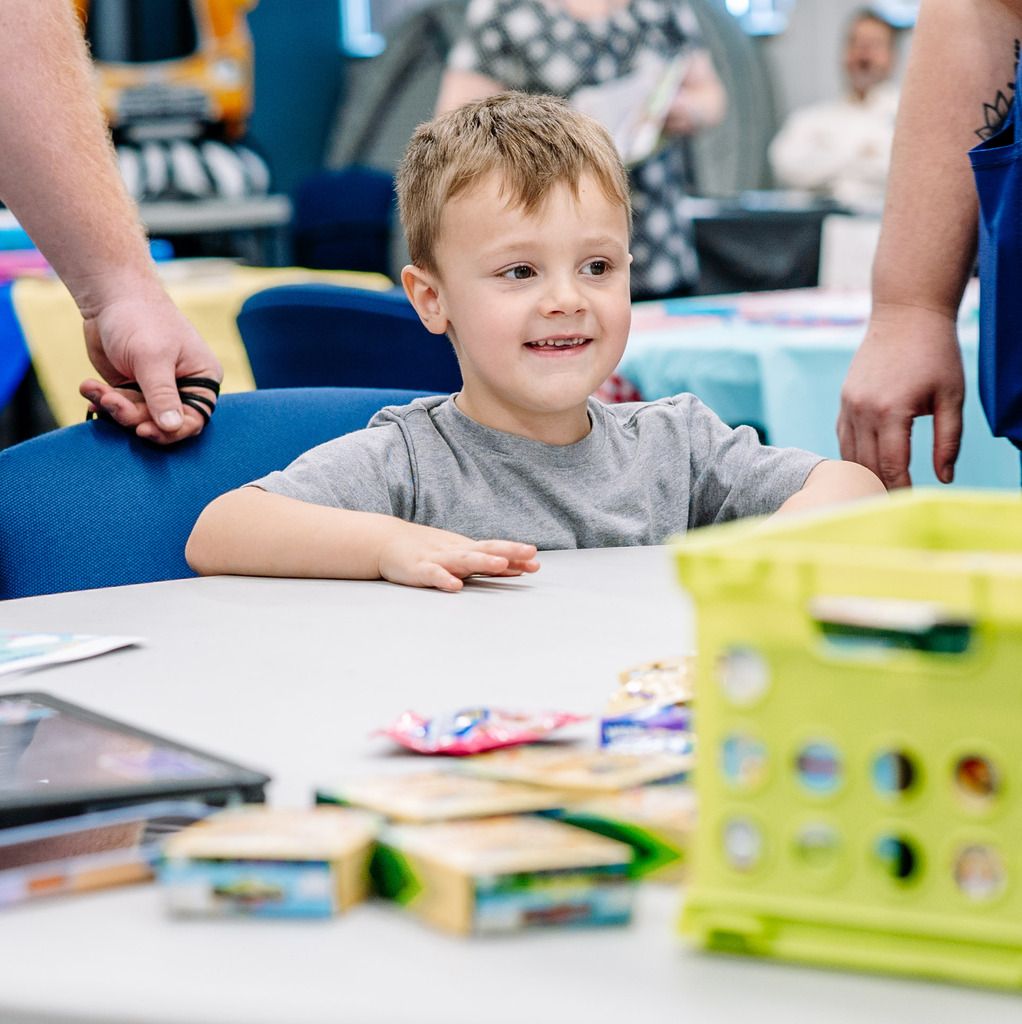 A young student sitting at a table and smiling. 