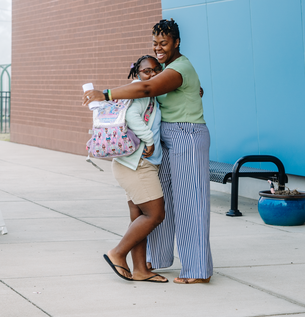 principal and student hugging outside of school.