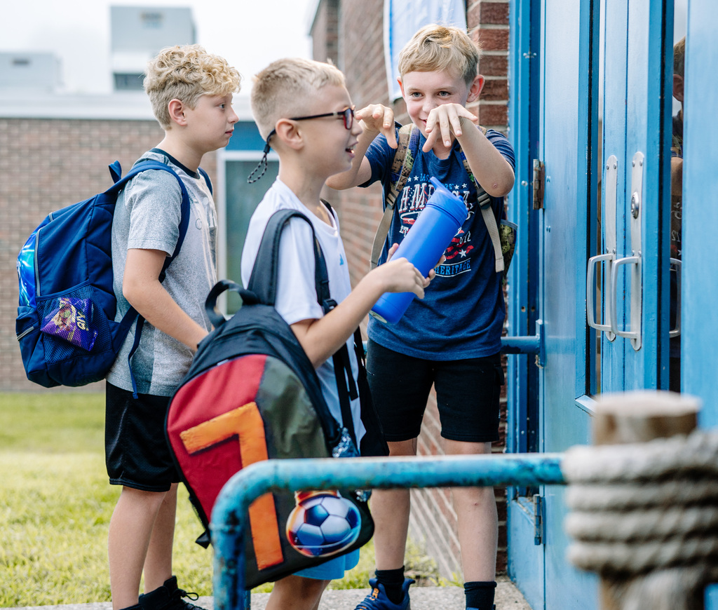 Three friends waiting for the doors the school doors to open.