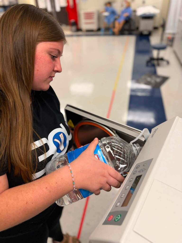 A high school student is filling up a machine with water in her medical assisting class.
