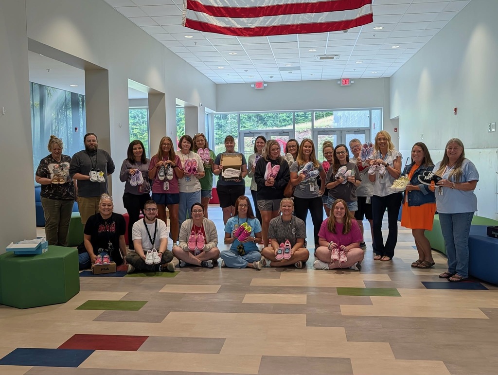 Teachers holding new pairs of shoes for students.