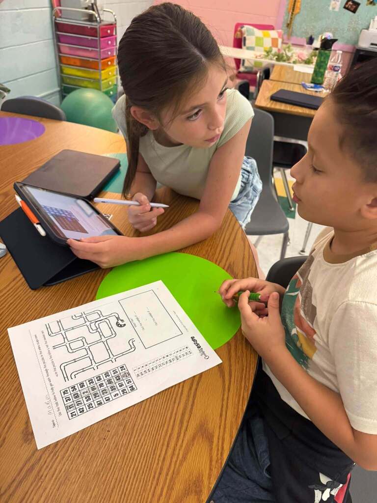 One student is looking at another student while they are mid discussion about a math problem.