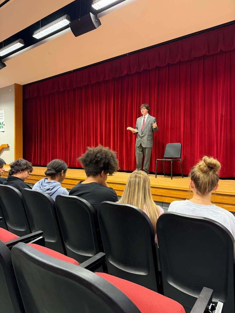 Students in the Nitro High School Auditorium, some in the audience seats and some on stage, doing a mock trial.