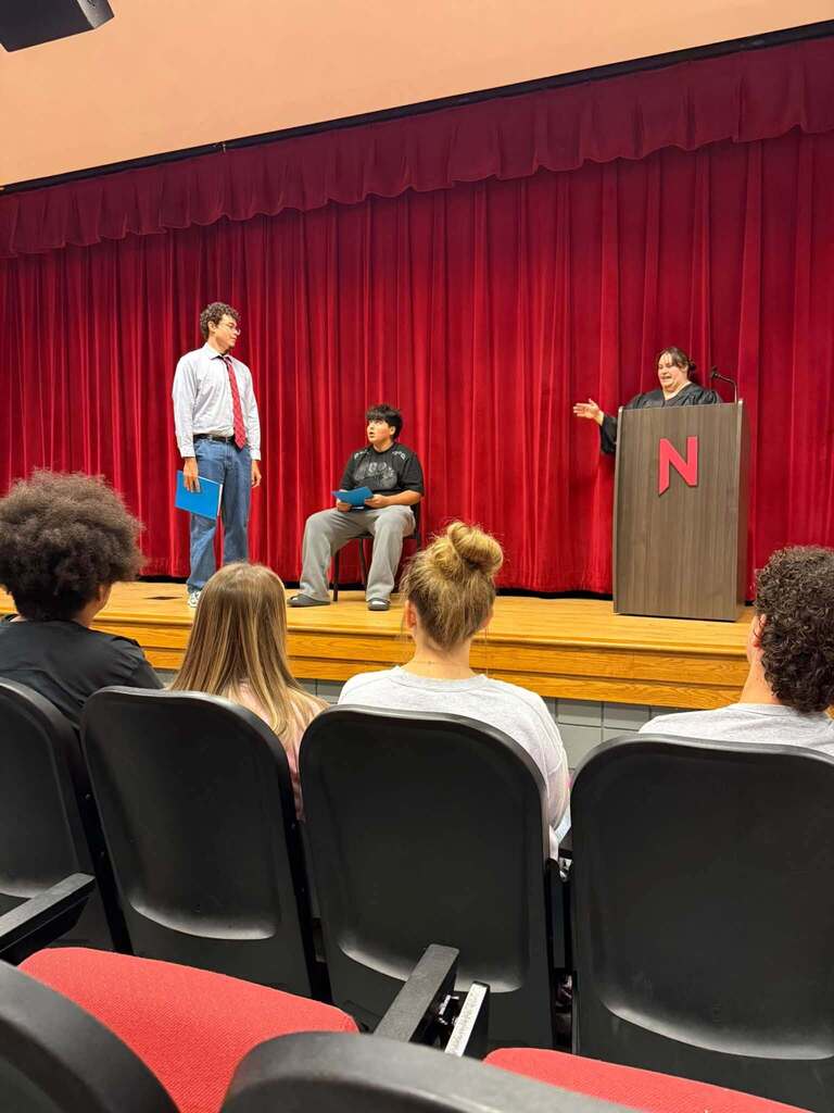 Students in the Nitro High School Auditorium, some in the audience seats and some on stage, doing a mock trial.