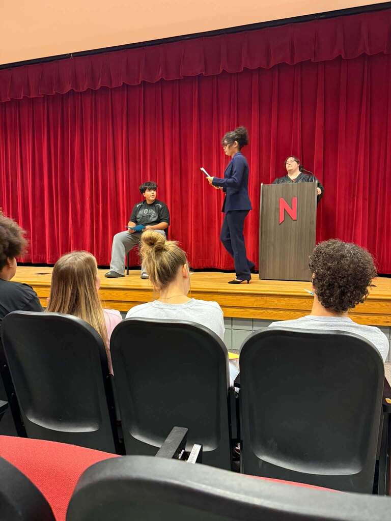 Students in the Nitro High School Auditorium, some in the audience seats and some on stage, doing a mock trial.