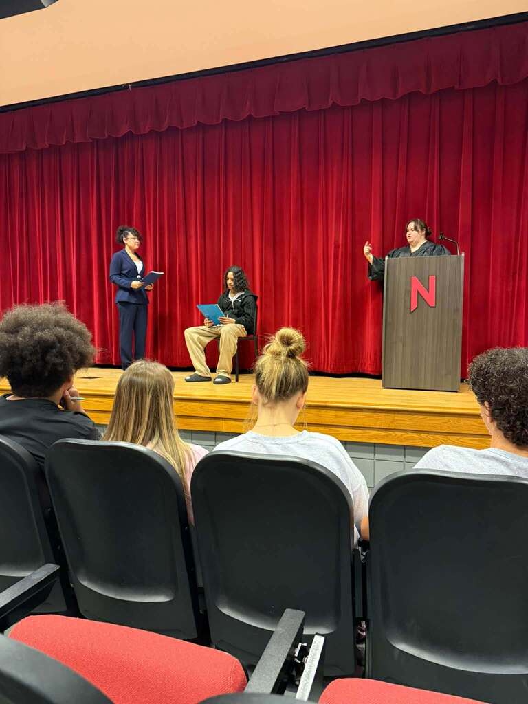 Students in the Nitro High School Auditorium, some in the audience seats and some on stage, doing a mock trial.