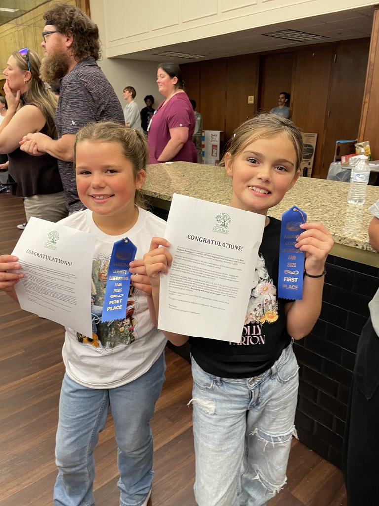 Two smiling girls proudly hold congratulations certificates and blue first-place ribbons at an indoor event, celebrating a cheerful competition win.