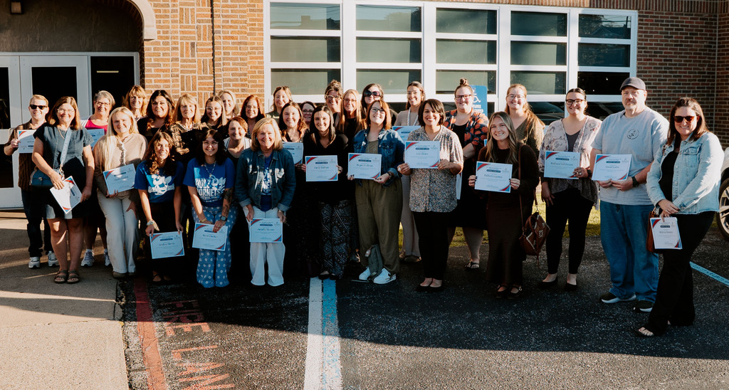 Teachers in grades 3 -5 holding up certificates after being recognized during a board of education meeting. They are standing in front of the KCS Board of Education Office. 