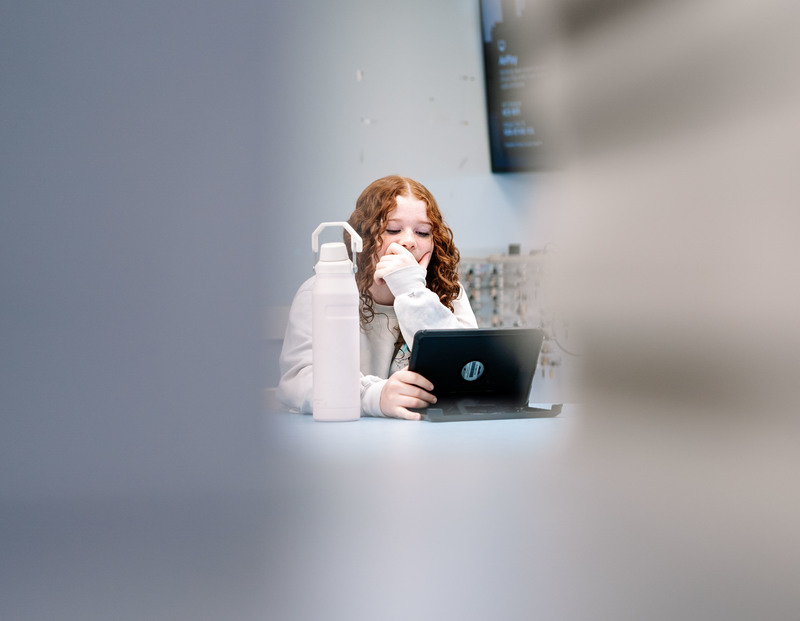 a nitro high school student sitting at a table doing the cipa lesson on her ipad.
