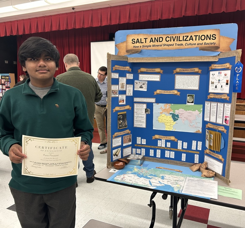 student standing beside his social studies fair project which is titled, "Salt and Civilizations."
