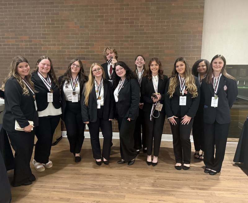 A group of Ben Franklin students are posing for a picture in front of a brick wall during the state leadership conference in Huntington.