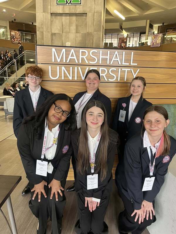 Six HOSA students from Ben Franklin are posing for a picture in front of a Marshall University Sign.