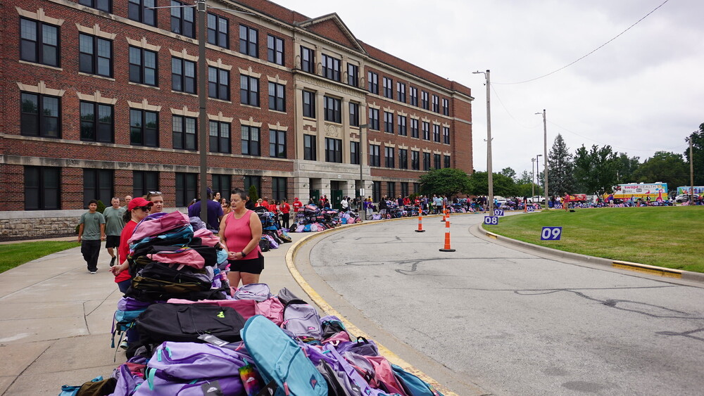 The driveway in front of east high school is lined with thousands of colorful backpacks awaiting pickup as volunteers stand at the ready