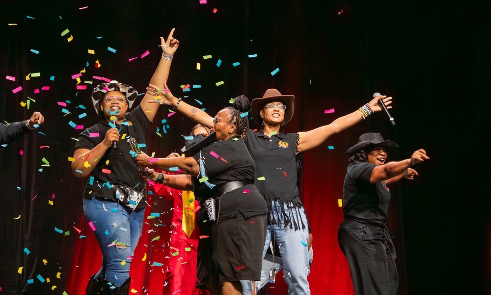 Teachers on stage celebrating as confetti falls through the air