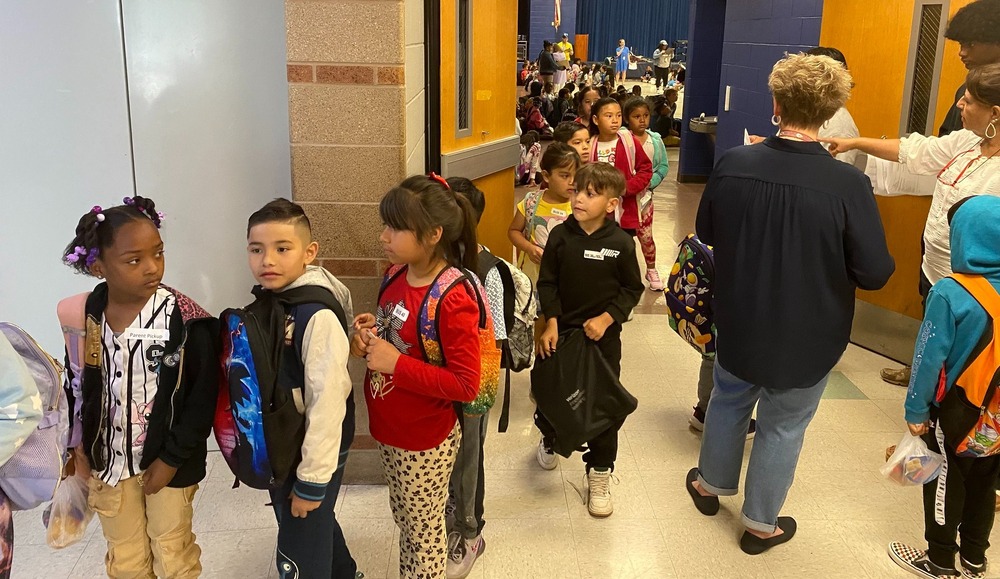 young students stand in a line entering a school cafeteria