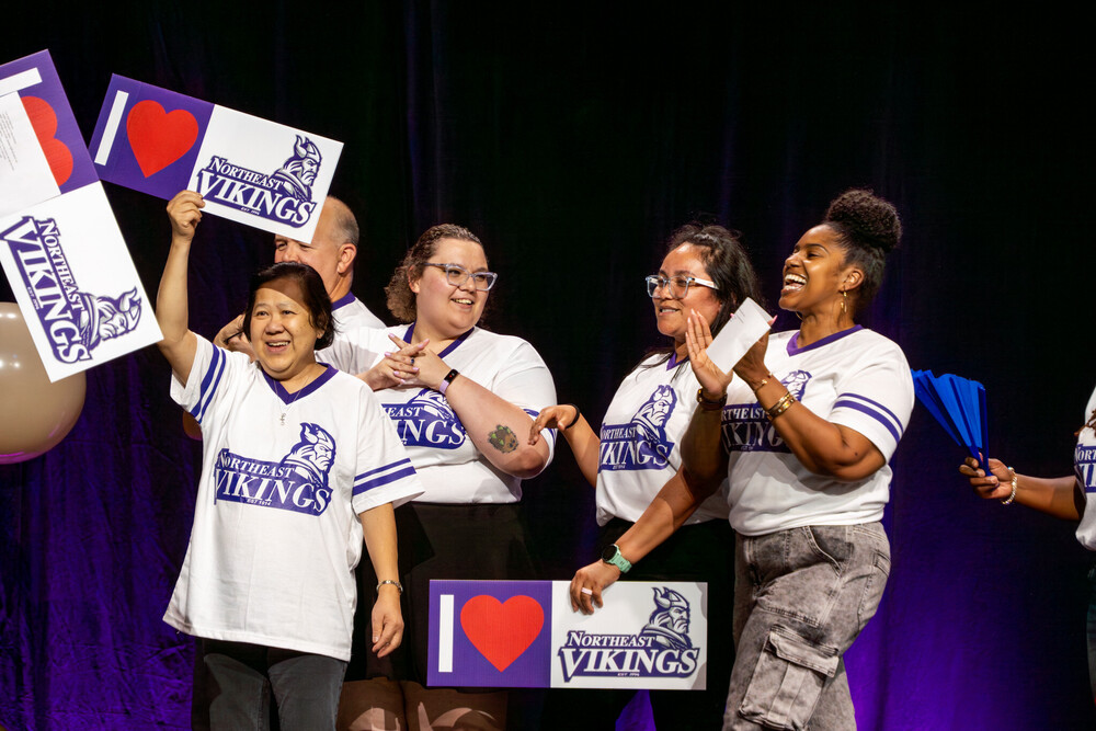 Teachers from Northeast High School wear matching school spirit jerseys on a stage