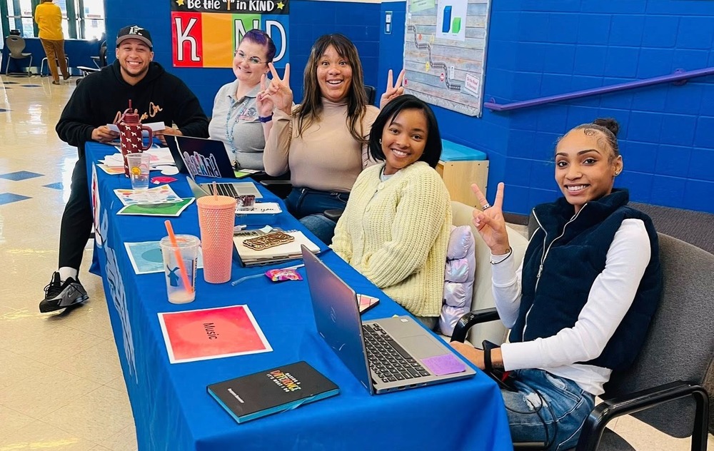Banneker staff sit at a table smiling and ready for parent-teacher conferences.